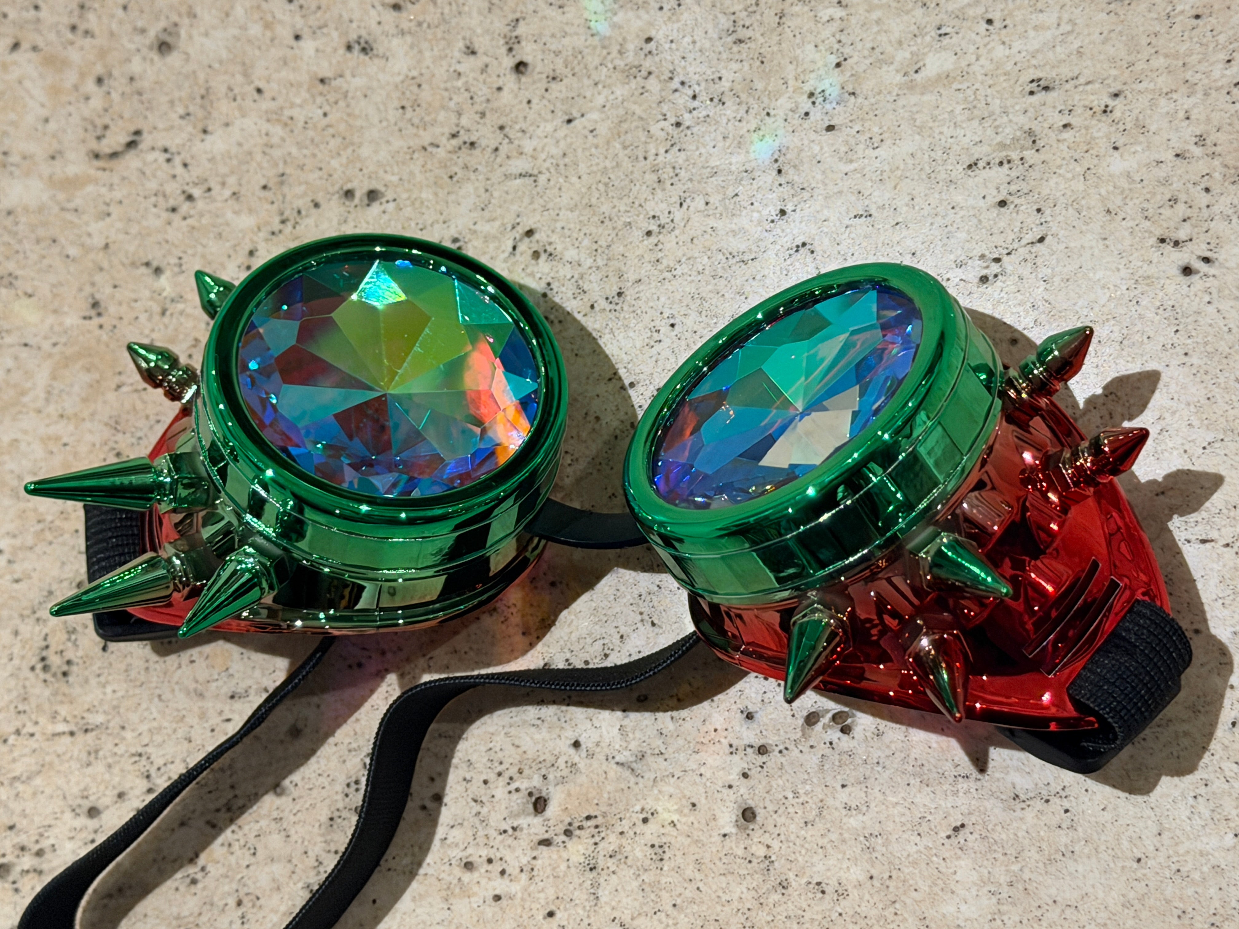 Pair of colorful goggles with green frames and spikes on a textured surface